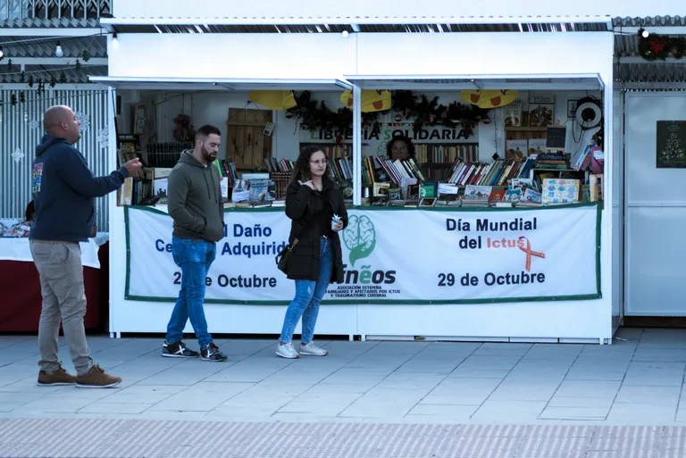 People browsing a market stall with books and crafts.