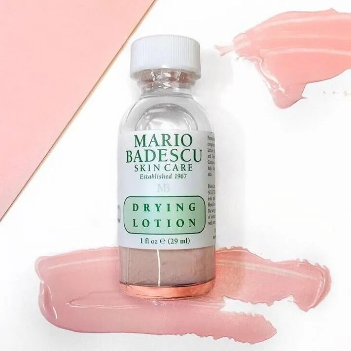 Tăm bông nhúng vào lớp bột hồng phía dưới đáy lọ Mario Badescu Drying Lotion không lắc chai chấm trực tiếp lên nốt mụn buổi tối